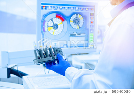 Laboratory assistant in rubber gloves working with a modern immunochemistry analyzer Laboratory assistant in rubber gloves working with a modern immunochemistry analyzer 69640080