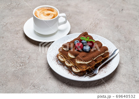 portion of Classic tiramisu dessert with raspberries, blueberries and cup of coffee on grey concrete background portion of Classic tiramisu dessert with raspberries, blueberries and cup of coffee on grey concrete background 69640532