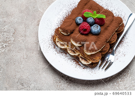 portion of Classic tiramisu dessert with raspberries and blueberries on grey concrete background portion of Classic tiramisu dessert with raspberries and blueberries on grey concrete background 69640533