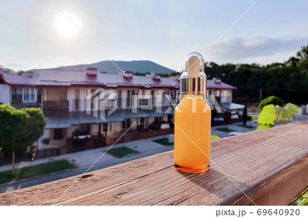 Glass cosmetic bottle with dropper pipette against the sunset. Beauty product for facial skin care, bottle for branding of medicine or cosmetics. Natural organic spa cosmetics concept. Selective Glass cosmetic bottle with dropper pipette against the sunset. Beauty product for facial skin care, bottle for branding of medicine or cosmetics. Natural organic spa cosmetics concept. Selective 69640920