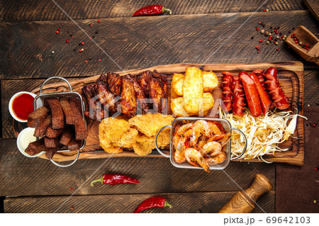 Fried beer snacks on the wooden board with sauces Fried beer snacks on the wooden board with sauces 69642103