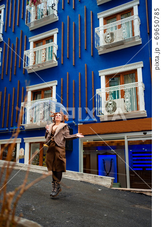 red-haired girl brown clothes blue wall umbrella red-haired girl brown clothes blue wall umbrella 69650785