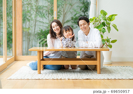 リビングの床で並んで座る3人家族のポートレートの写真素材