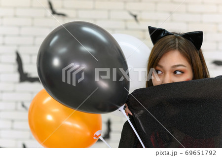 Portrait of beautiful young asian woman wearing witch costume posing with balloons on background decorated for party concept - Free space for copy text 69651792
