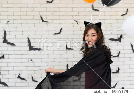 Portrait of beautiful young asian woman wearing witch costume posing with balloons on background decorated for party concept - Free space for copy text Portrait of beautiful young asian woman wearing witch costume posing with balloons on background decorated for party concept - Free space for copy text 69651793