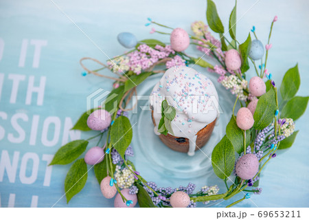 Easter cake in the center of a wreath of spring flowers on a blue vintage background with text and copy space Easter cake in the center of a wreath of spring flowers on a blue vintage background with text and copy space 69653211