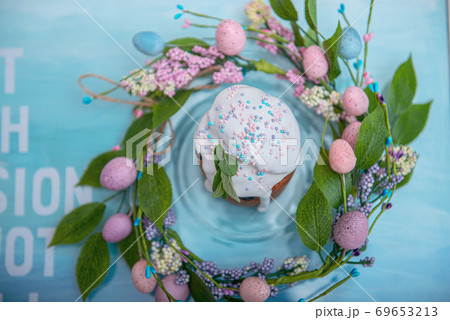 Easter cake in the center of a wreath of spring flowers on a blue vintage background with copy space Easter cake in the center of a wreath of spring flowers on a blue vintage background with copy space 69653213