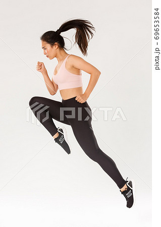 Sport, gym and healthy body concept. Full length of serious focused female runner, motion shot of girl running in air, fitness training of cute slim sportswoman, athlete workout in active wear 69653584