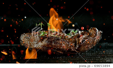 Tasty beef steak on cast iron grate with fire flames. 69653894