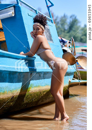 Asian model in bikini posing with old fishing boat Asian model in bikini posing with old fishing boat 69653945
