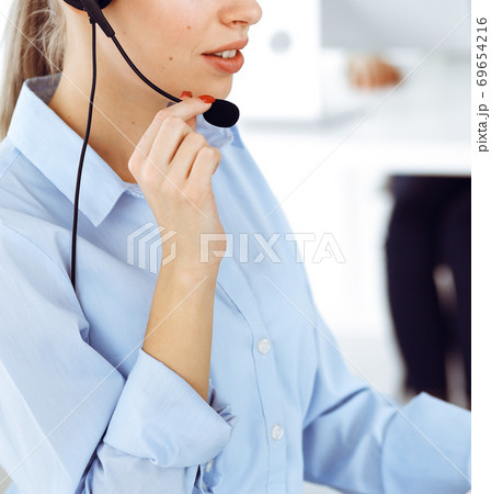 Female call operator is using computer and headset for consulting clients online, close-up. Group of diverse people working as customer service occupation Female call operator is using computer and headset for consulting clients online, close-up. Group of diverse people working as customer service occupation 69654216