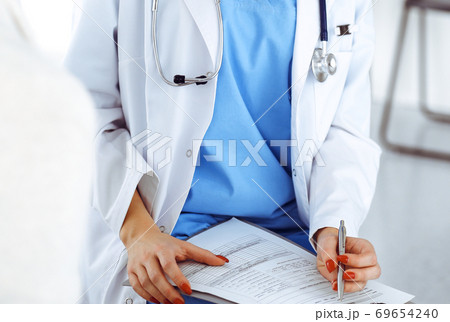 Woman - doctor consults her female patient while using clipboard and medication history record. Medicine concept Woman - doctor consults her female patient while using clipboard and medication history record. Medicine concept 69654240