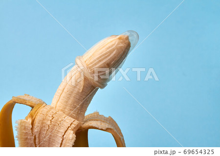 Half peeled banana with condom. Half peeled banana with condom. 69654325
