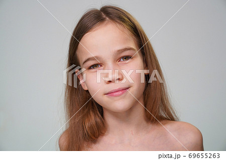 teen girl with blond hair against a white wall 69655263