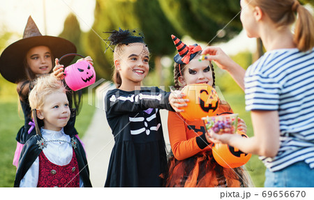 Woman giving treats to children in costumes. 69656670