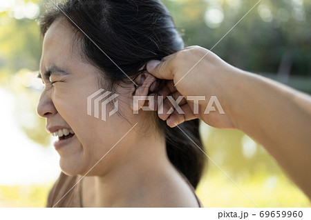 Disobedient asian woman being punished with ear pulling angry husband is twisting the ear of the wife and threatening while scolding his, female people receives physical attacked screaming from pain  69659960