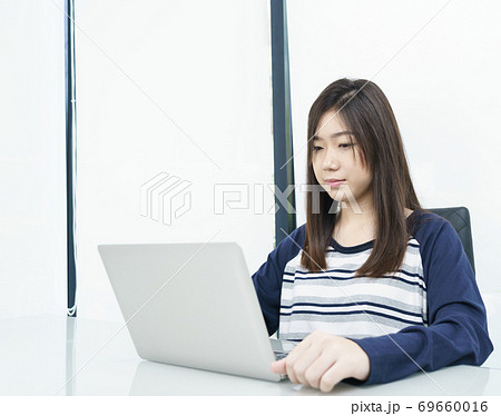 Young female student  sitting in living room and learning online 69660016