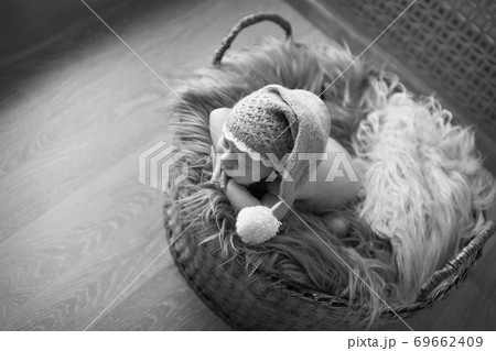 a small child in a basket sleeps in a warm knitted hat with a pompom a small child in a basket sleeps in a warm knitted hat with a pompom 69662409