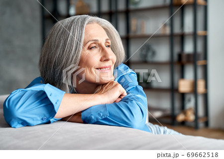 Happy relaxed mature old woman resting dreaming sitting on couch at home. 69662518