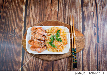 Udon noodles and fried cocktail prawns on a plate. 69664491