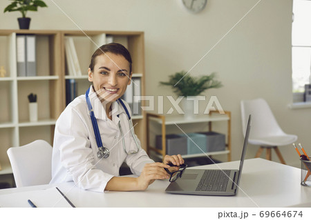 Woman doctor looking at camera during online meeting on laptop Woman doctor looking at camera during online meeting on laptop 69664674
