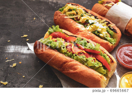 Hot dogs with various fillings. Dark background. food background with copy space. Hot dogs with mustard and ketchup, lettuce, cheese and tomatoes. Close up 69665667