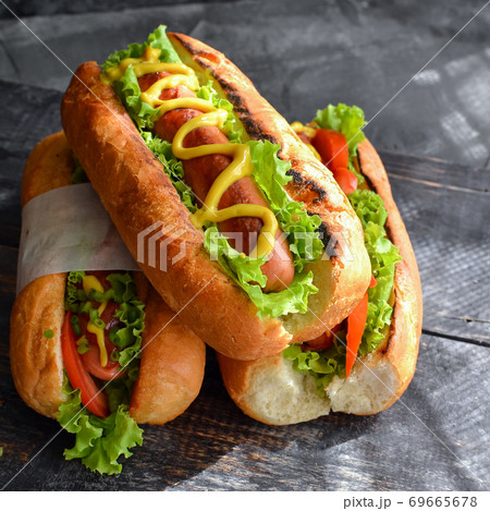 Hot dogs with various fillings. Dark background. food background with copy space. Hot dogs with mustard and ketchup, lettuce, cheese and tomatoes. Close up Hot dogs with various fillings. Dark background. food background with copy space. Hot dogs with mustard and ketchup, lettuce, cheese and tomatoes. Close up 69665678