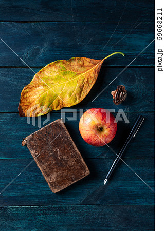 Moody autumnal composition. A vibrant fall leaf with an apple, a notebook, and an ink pen Moody autumnal composition. A vibrant fall leaf with an apple, a notebook, and an ink pen 69668211