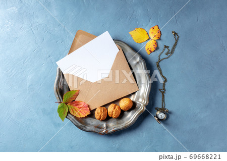 Autumn stationery mockup, overhead flat lay shot of a greeting card or invitation in a brown craft envelope, on a tray with leaves and nuts 69668221