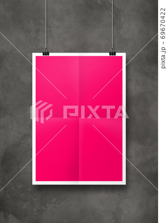 Pink folded poster hanging on a concrete wall with clips 69670422