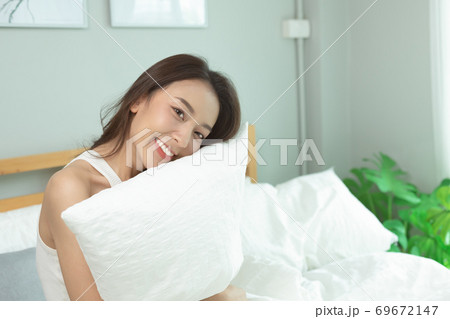 Asian women wake up happy and smile on white bed in bedroom. 69672147