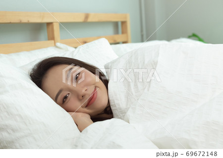 Asian women wake up happy and smile on white bed in bedroom. Asian women wake up happy and smile on white bed in bedroom. 69672148