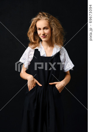Satisfied young girl in pantsuit and shirt posing over black background Satisfied young girl in pantsuit and shirt posing over black background 69673094