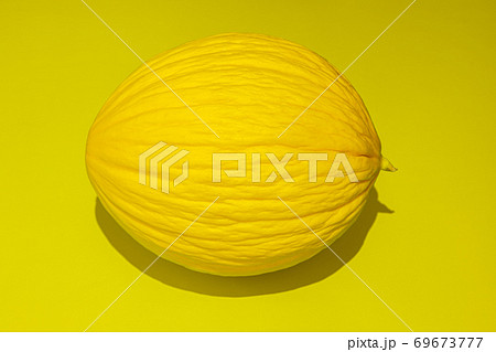 Yellow melon on bright yellow background. Food concept. Flat lay with shadow Yellow melon on bright yellow background. Food concept. Flat lay with shadow 69673777
