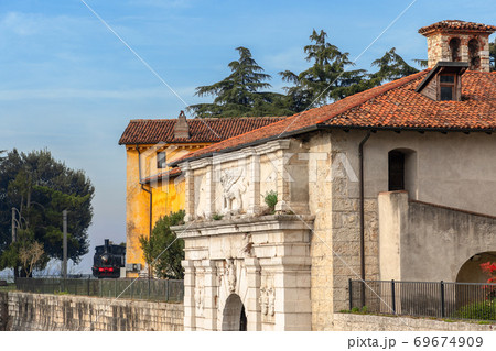Entrance to the medieval castle of Brescia and an old locomotive installed in the park Entrance to the medieval castle of Brescia and an old locomotive installed in the park 69674909