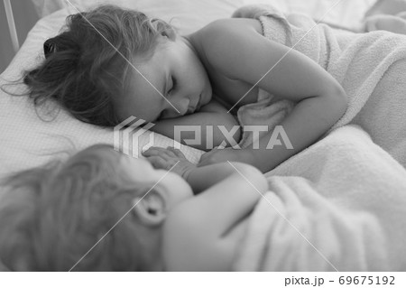 small girl with sister sleep together in bed home 69675192
