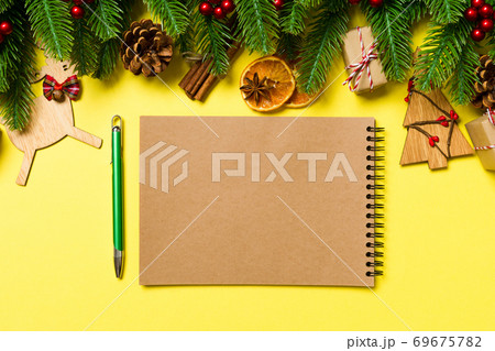 Top view of notebook on yellow background made of Christmas decorations. New Year time concept 69675782