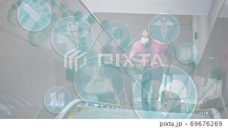 Digital illustration of medical icons over a man wearing coronavirus covid19 mask Digital illustration of medical icons over a man wearing coronavirus covid19 mask 69676269