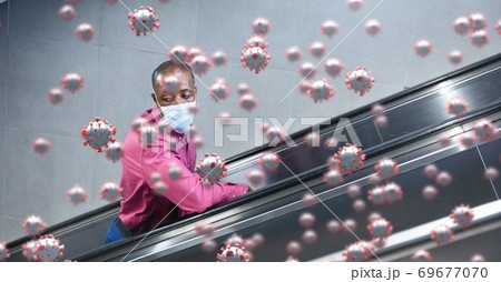 Covid-19 cells against man wearing a face mask using escalator 69677070