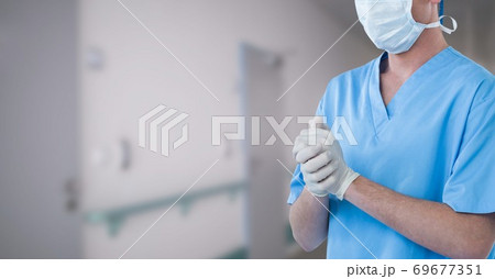 Mid section of male doctor in hospital wearing coronavirus covid19 mask Mid section of male doctor in hospital wearing coronavirus covid19 mask 69677351