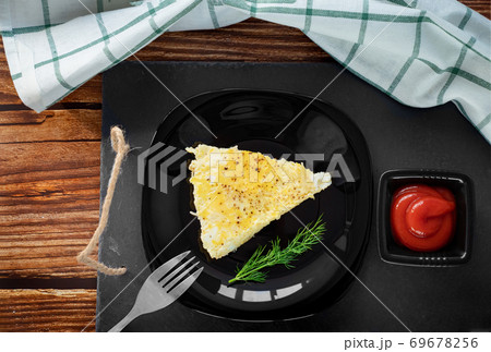 piece of omelet on black plate with ketchup. piece of omelet on black plate with ketchup. 69678256