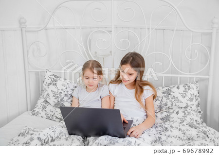 sisters study on computer online at home bed. 69678992