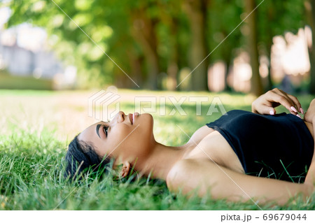 Pretty afro american woman relaxing on grass in park 69679044