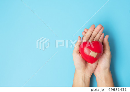 Woman holding Red heart shape on blue background. Healthcare, life Insurance, health and World Heart Day concept Woman holding Red heart shape on blue background. Healthcare, life Insurance, health and World Heart Day concept 69681431