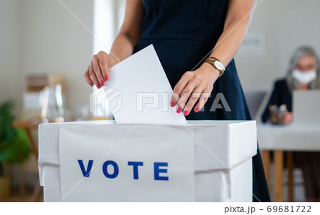 Unrecognizable woman putting her vote in the ballot box, usa and coronavirus elections. Unrecognizable woman putting her vote in the ballot box, usa and coronavirus elections. 69681722