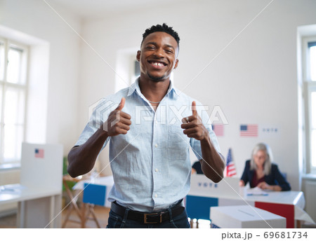 Happy african-american man looking at camera in the polling place, usa elections. Happy african-american man looking at camera in the polling place, usa elections. 69681734