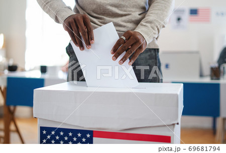 Unrecognizable african-american man putting his vote in the ballot box, usa elections and coronavirus. Unrecognizable african-american man putting his vote in the ballot box, usa elections and coronavirus. 69681794