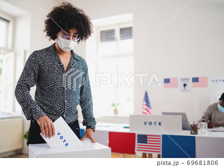 Young man putting his vote in the ballot box, usa elections and coronavirus. Young man putting his vote in the ballot box, usa elections and coronavirus. 69681806
