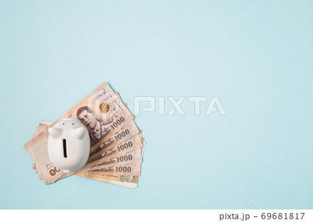 Saving piggy bank with Thai currency, 1000 Baht, money banknote of Thailand on blue background Saving piggy bank with Thai currency, 1000 Baht, money banknote of Thailand on blue background 69681817