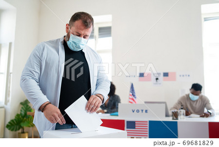Mature man putting his vote in the ballot box, usa elections and coronavirus. 69681829